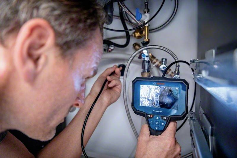 Ein Techniker inspiziert mit einem Endoskop eine Maschine. Der Bildschirm zeigt das Innere der Maschine.