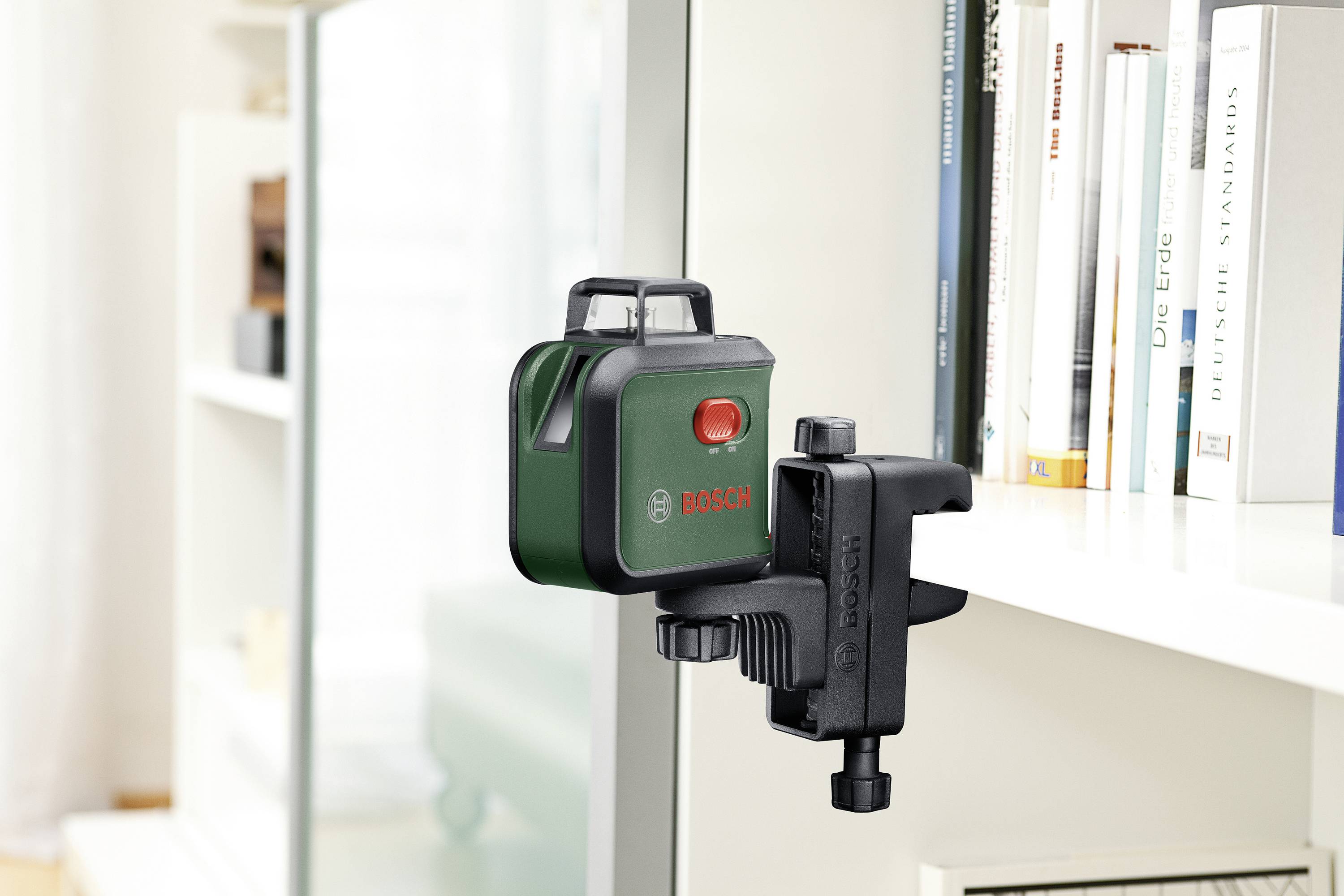 Ein Laser-Entfernungsmesser der Marke Bosch, befestigt an einem Regal, zeigt die Anwendung des Geräts in einem häuslichen Umfeld.