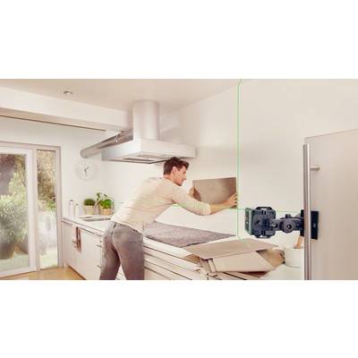 Ein Mann richtet mit einer Laser-Wasserwaage eine Kachel an der Wand in einer modernen Küche aus. Im Hintergrund ist ein Fenster.