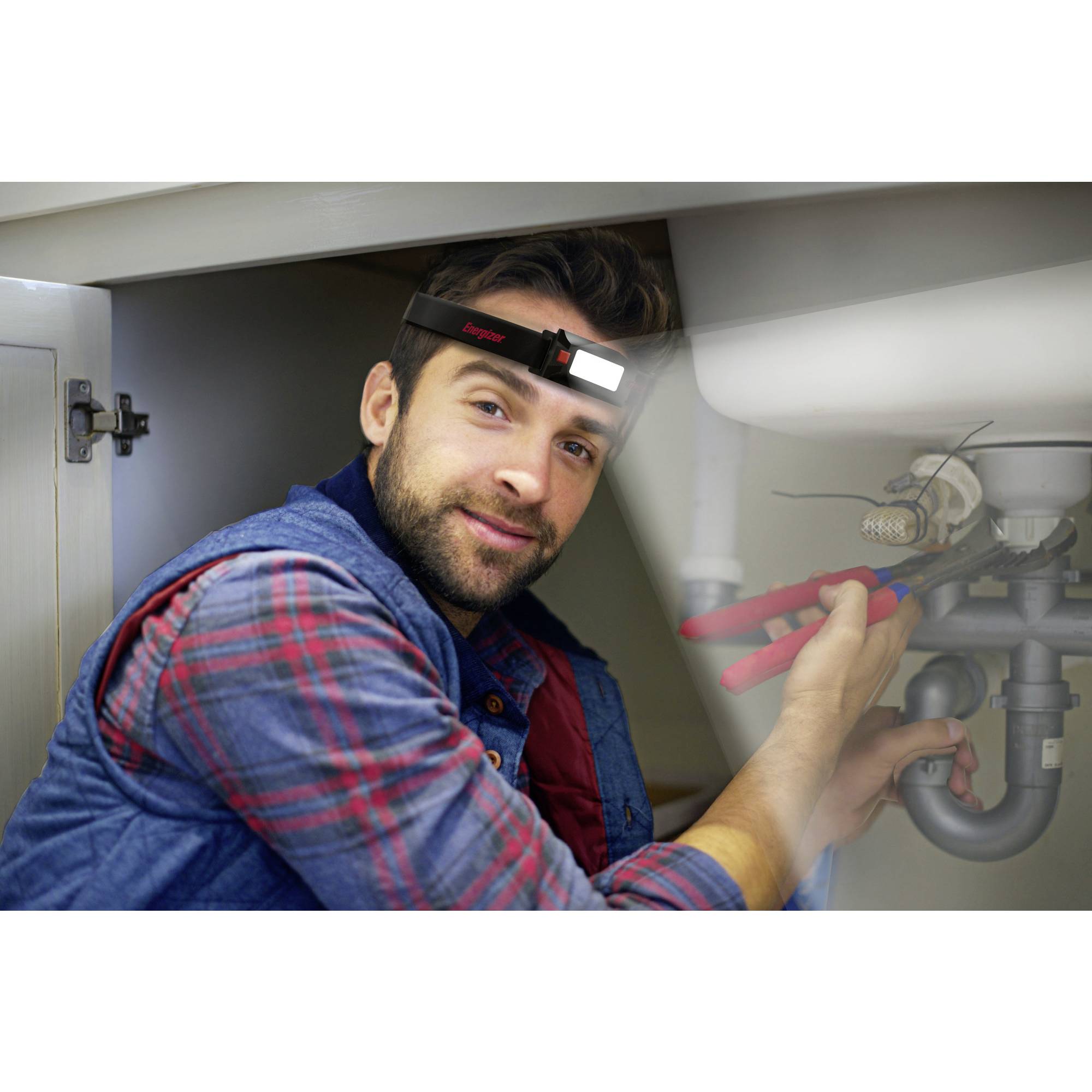 Ein Mann mit Stirnlampe repariert Rohre unter einem Waschbecken, hält eine Zange.