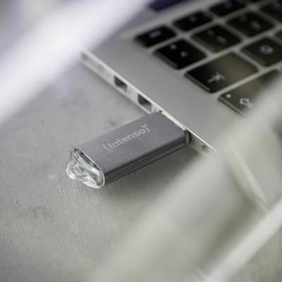 Ein USB-Stick ist in einen Laptop eingesteckt. Der Markenname 'Intenso' ist auf dem Stick sichtbar. Der Laptop liegt auf einem Tisch.