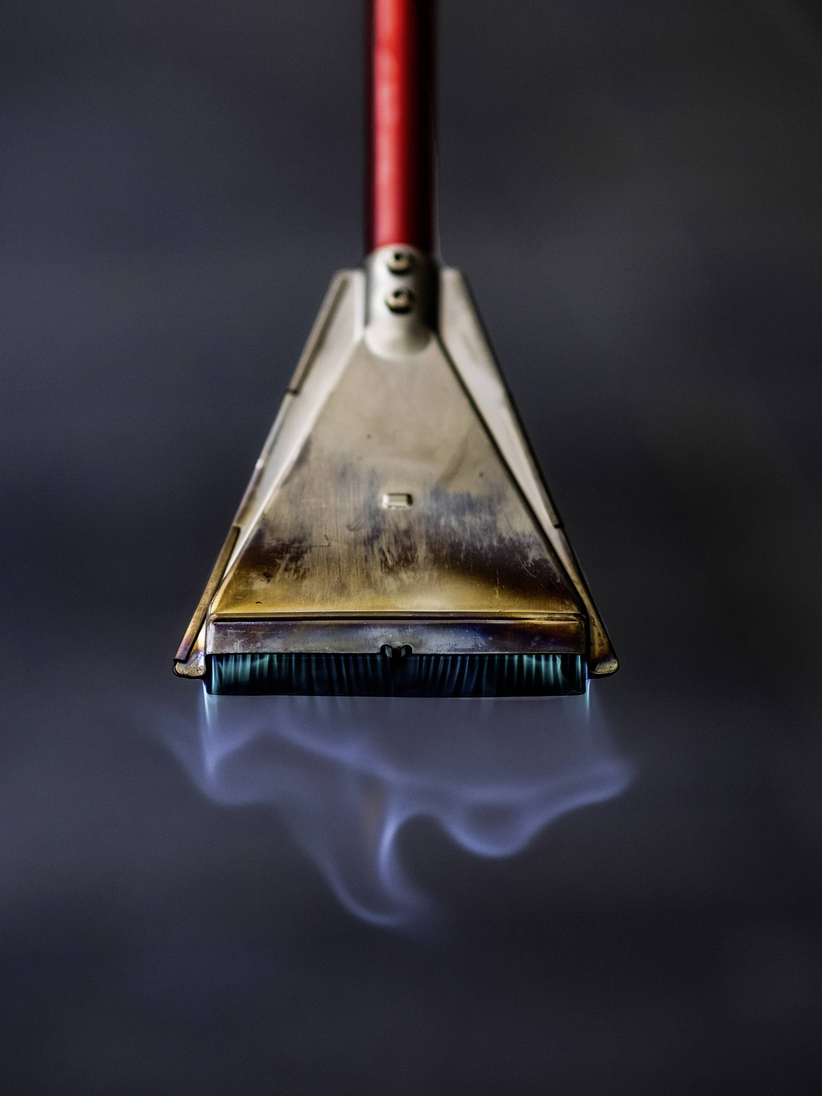 Eine Reinigungsdüse mit rotem Griff sprüht Dampf aus, vor einem dunklen Hintergrund, zeigt professionelle Reinigungstechnik.