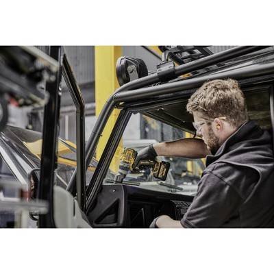 Eine Person in Schutzbrille und Handschuhen arbeitet an einem Fahrzeug mit einem Elektrowerkzeug. Sie befestigt oder repariert Teile.