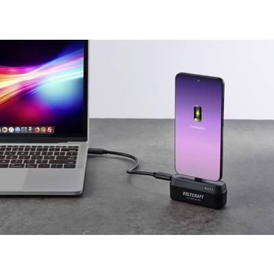 Ein Smartphone wird mit einem Kabel von einem Laptop aufgeladen. Der Bildschirm des Smartphones zeigt ein Ladesymbol.