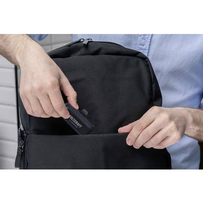 Person legt ein Werkzeugset in eine schwarze Rucksacktasche. Die Person trägt ein hellblaues Hemd.