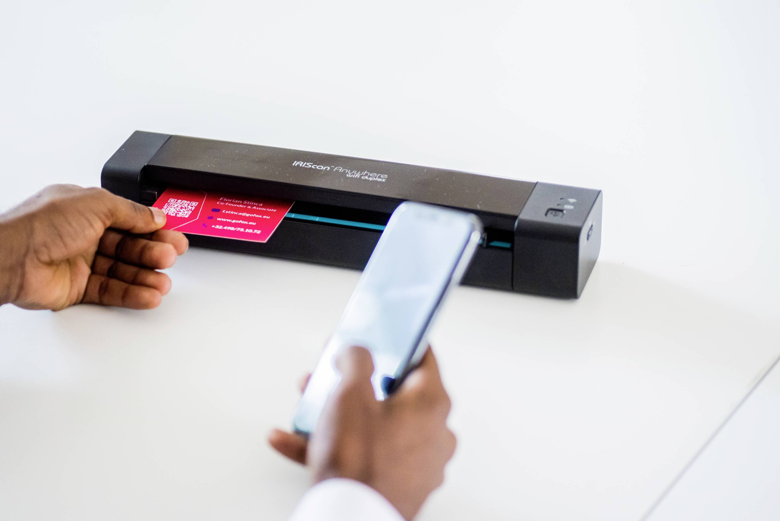 Eine Person scannt mit einem tragbaren Scanner ein QR-Code-Dokument. Im Vordergrund hält die Person ein Smartphone.