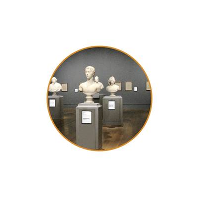 Büste in einem Museum auf einem Podest, im Hintergrund weitere Büsten und Infotafeln an dunkler Wand.
