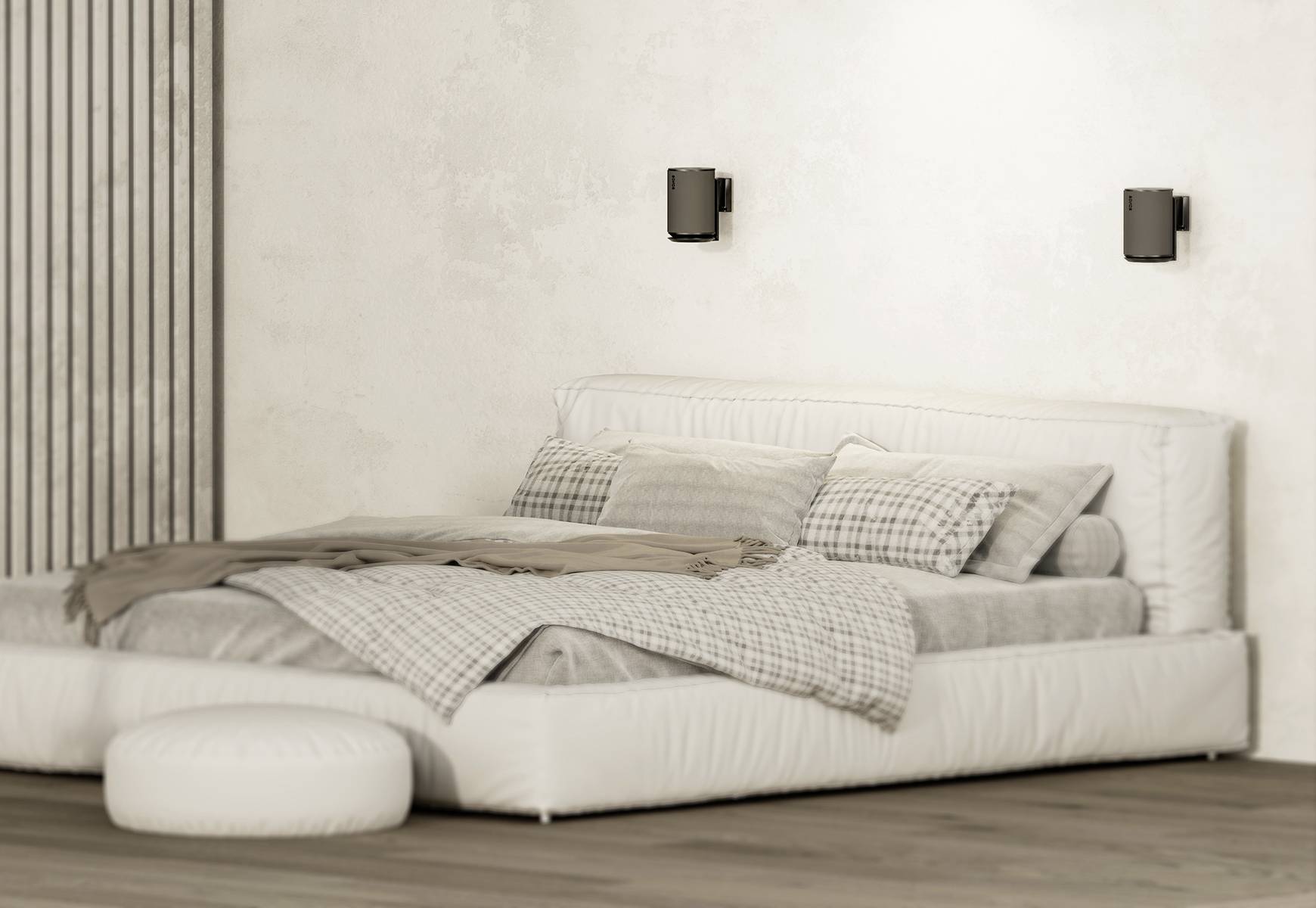 Ein modernes Schlafzimmer mit einem großen, weißen Bett, gemusterten Kissen und grauen Bettdecken. Zwei Wandleuchten an der Wand.