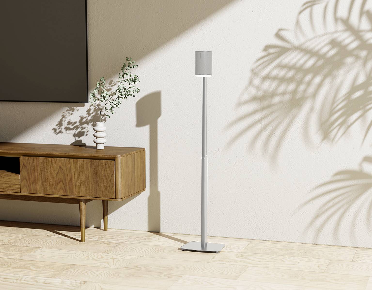 Ein Wohnzimmer mit Holzschrank, darauf eine Vase mit grünen Zweigen. Daneben ein weißer Standlautsprecher auf Holzboden, beleuchtet von Sonnenlicht.