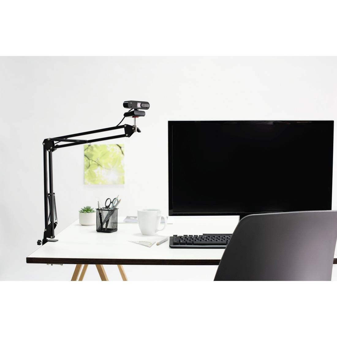 Ein minimalistischer Schreibtisch mit Computerbildschirm, Tastatur, Kaffeetasse und Stifthalter vor einer weißen Wand.