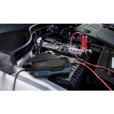 Ein Autobatterieladegerät ist an eine Autobatterie angeschlossen. Rote und schwarze Kabel verbinden das Gerät mit den Batterieklemmen.