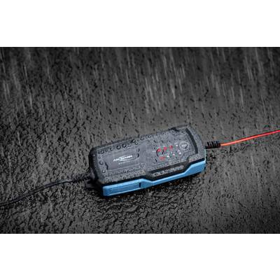 Ein batteriebetriebenes schwarzes und blaues Gerät mit leuchtenden roten LED-Anzeigen liegt auf nasser, regnerischer Oberfläche.