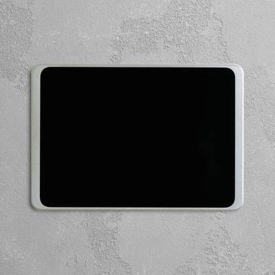 Ein Tablet mit schwarzem Bildschirm liegt auf einer grauen Oberfläche.