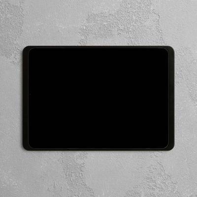 Ein Tablet mit schwarzem Bildschirm liegt flach auf einer grauen, strukturierten Oberfläche.