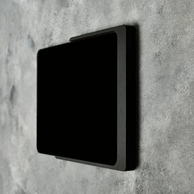 An der Wand ist ein rechteckiger, schwarzer Lichtschalter zu sehen.