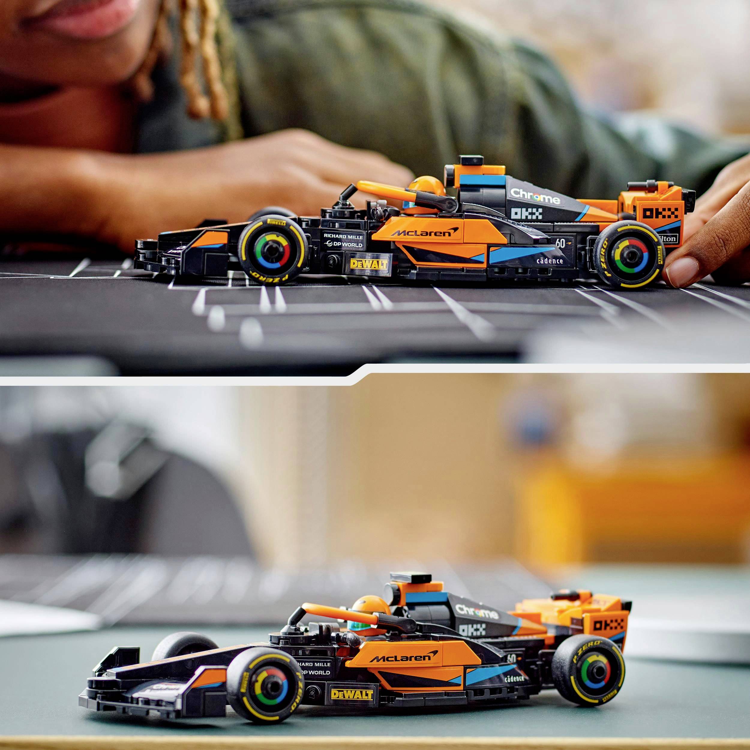 Ein Kind spielt mit einem maßstabsgetreuen Modellauto eines Formel-1-Rennwagens, das in leuchtenden Farben gestaltet ist.