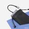 Ein tragbares Ladegerät wird teilweise aus einer schwarzen Tasche herausgezogen. Ein USB-Kabel ist angeschlossen.