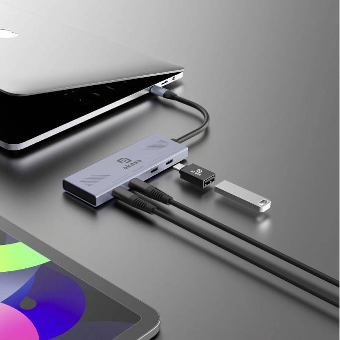 Ein Laptop ist über einen USB-C-Hub mit mehreren Geräten verbunden, darunter ein USB-Stick und Audiokabel.