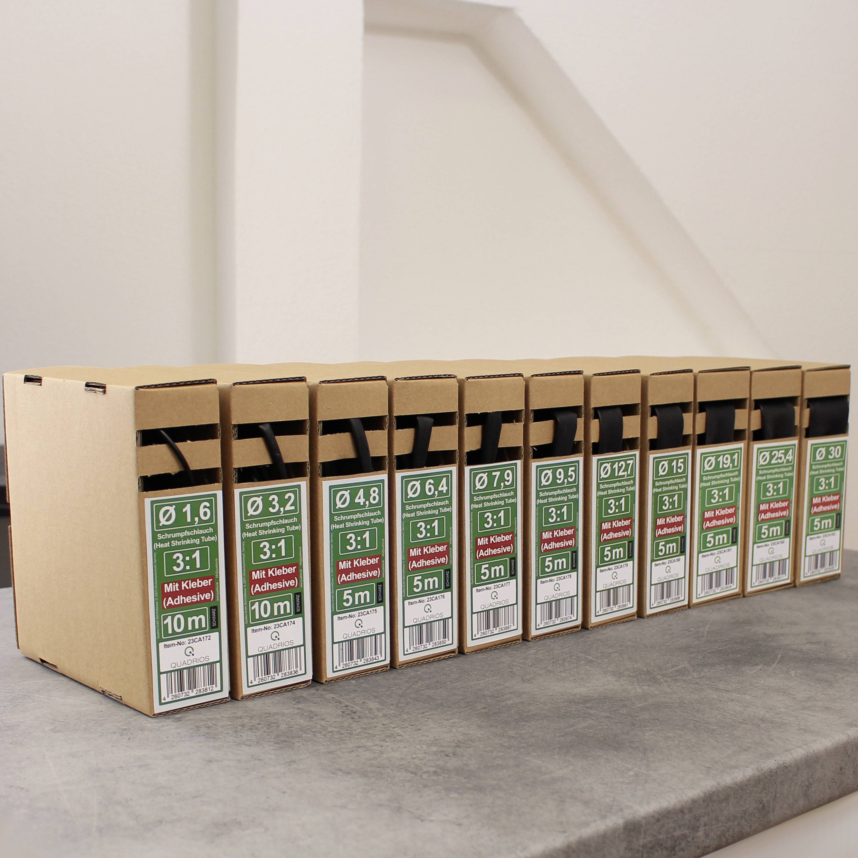 '11 Packungen 3-in-1 KFZ-Mikroklebeband, Ø von 0,6 bis 19 mm, Längen bis 15 m, in einem braunen Karton auf einer grauen Oberfläche.'