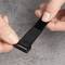 Eine Hand zieht einen schwarzen Klettverschlussstreifen fest, der möglicherweise zum Befestigen oder Organisieren von Gegenständen dient.