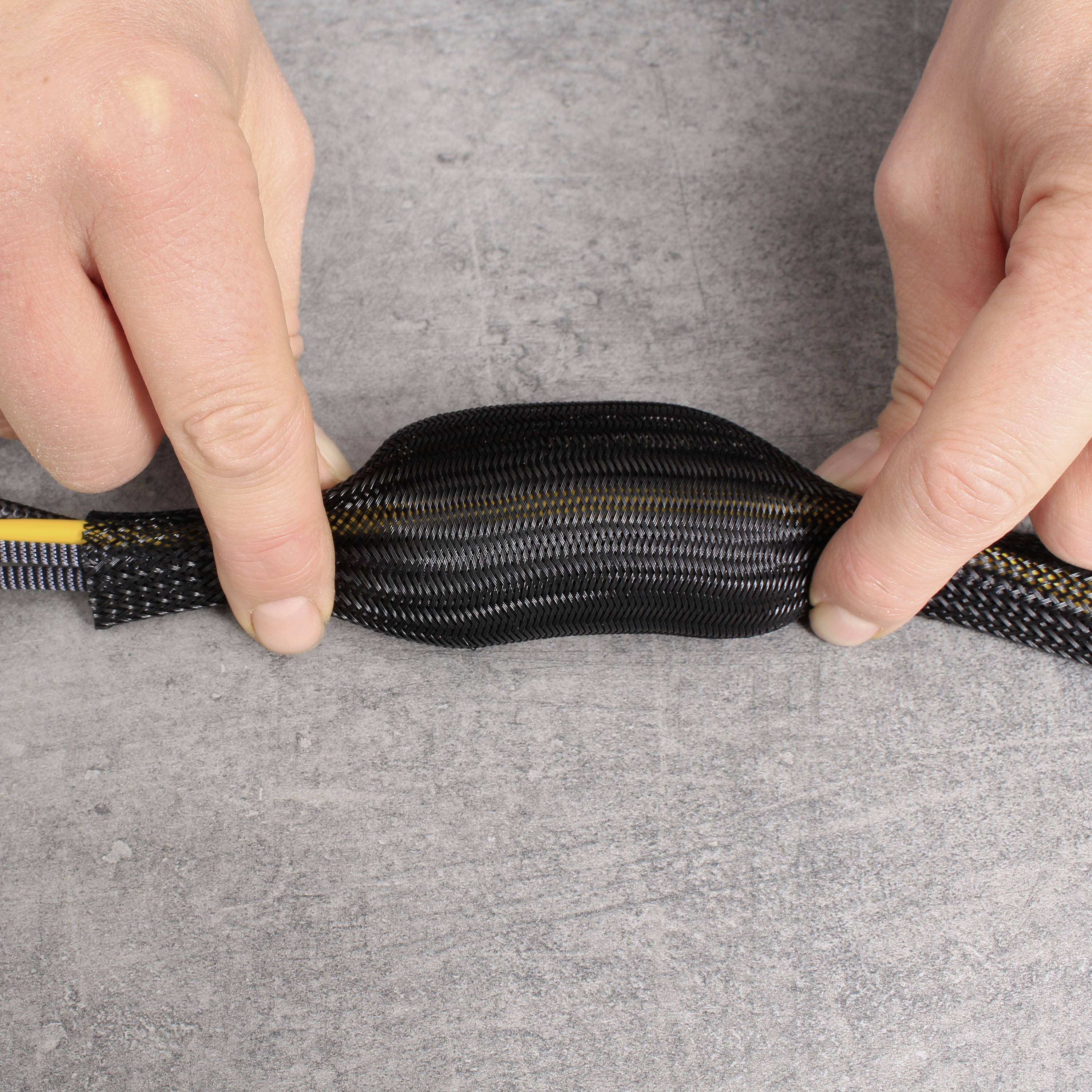 Zwei Hände ziehen ein flexibles Schutzrohr über mehrere Kabel, um sie zu bündeln und zu sichern.