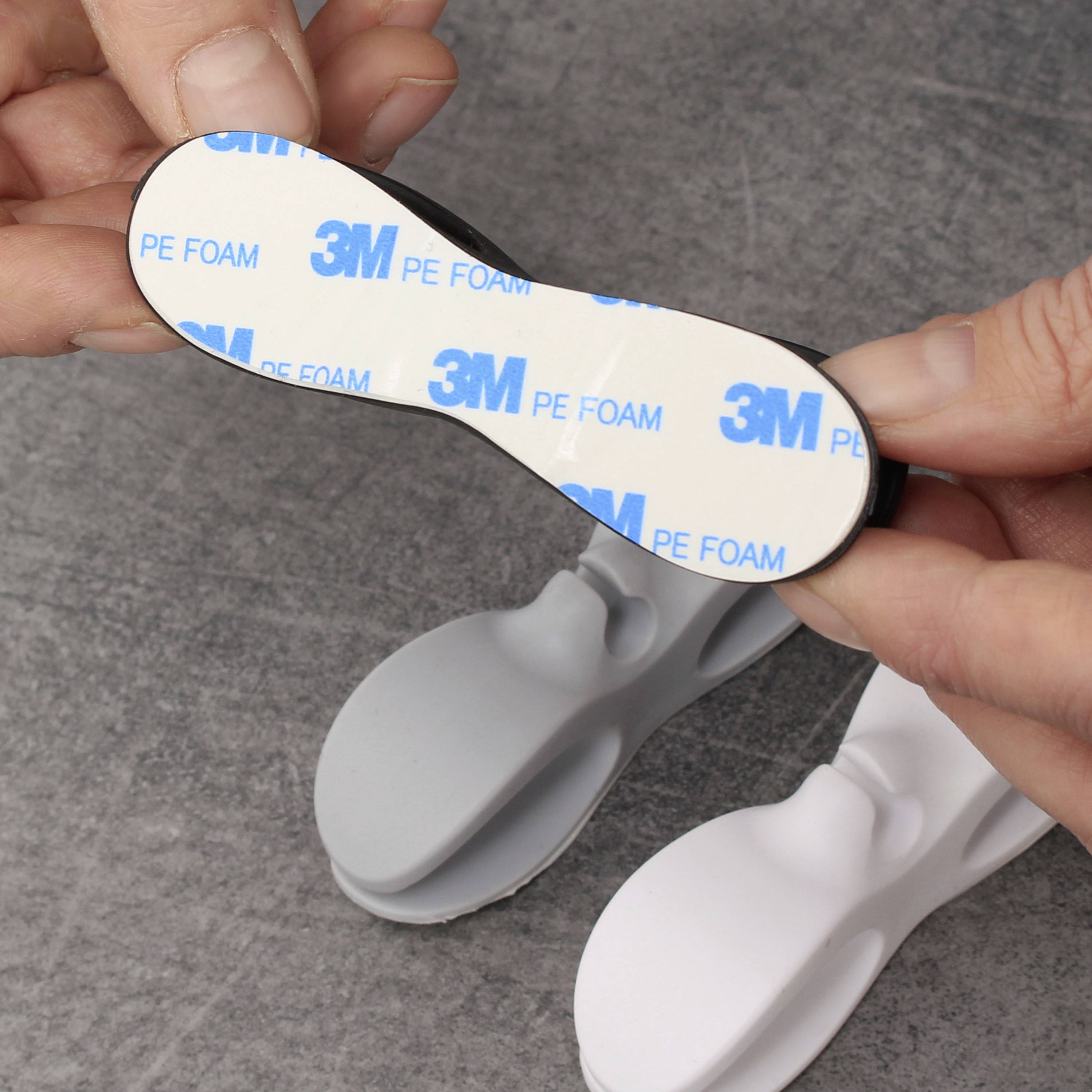 Eine Person hält eine selbstklebende Schaumstoff-Unterlage mit der Aufschrift '3M PE FOAM', bereit zur Befestigung auf einer Oberfläche.