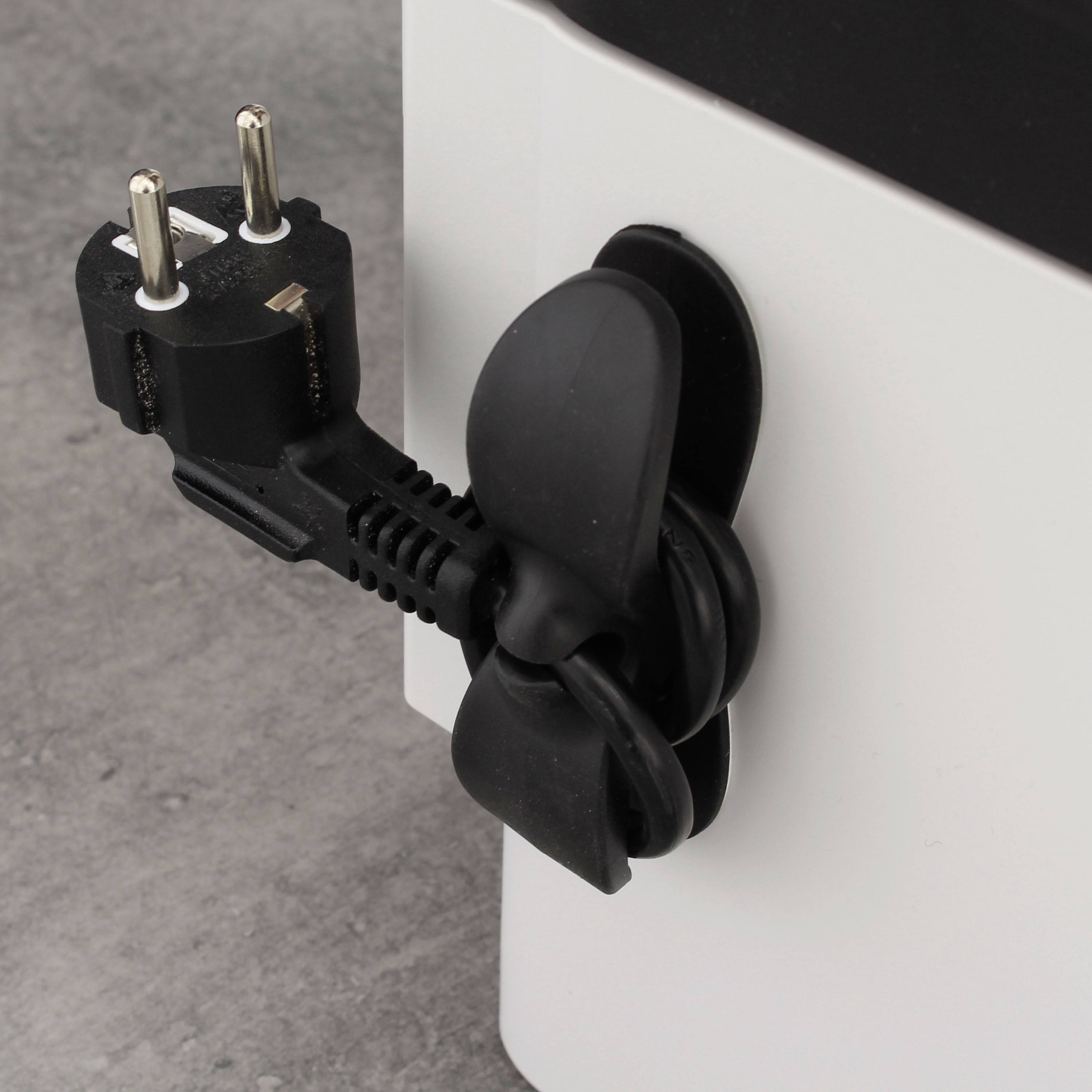 Schwarzes Kabel mit Stecker ordentlich aufgewickelt und per Kabelklemme fixiert, steckt in einer weißen Steckdose an grauer Wand.