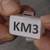 Hand hält kleines Kunststoffetikett mit der Aufschrift 'KM3'.