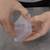 Zwei Hände halten einen transparenten Plastikbehälter. Die eine Hand öffnet den Deckel leicht. Hintergrund ist eine graue Oberfläche.