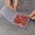 Eine Hand hält eine rote LED, während eine andere Hand eine Schachtel mit vielen roten LEDs öffnet. Die LEDs sind lose in der Box.