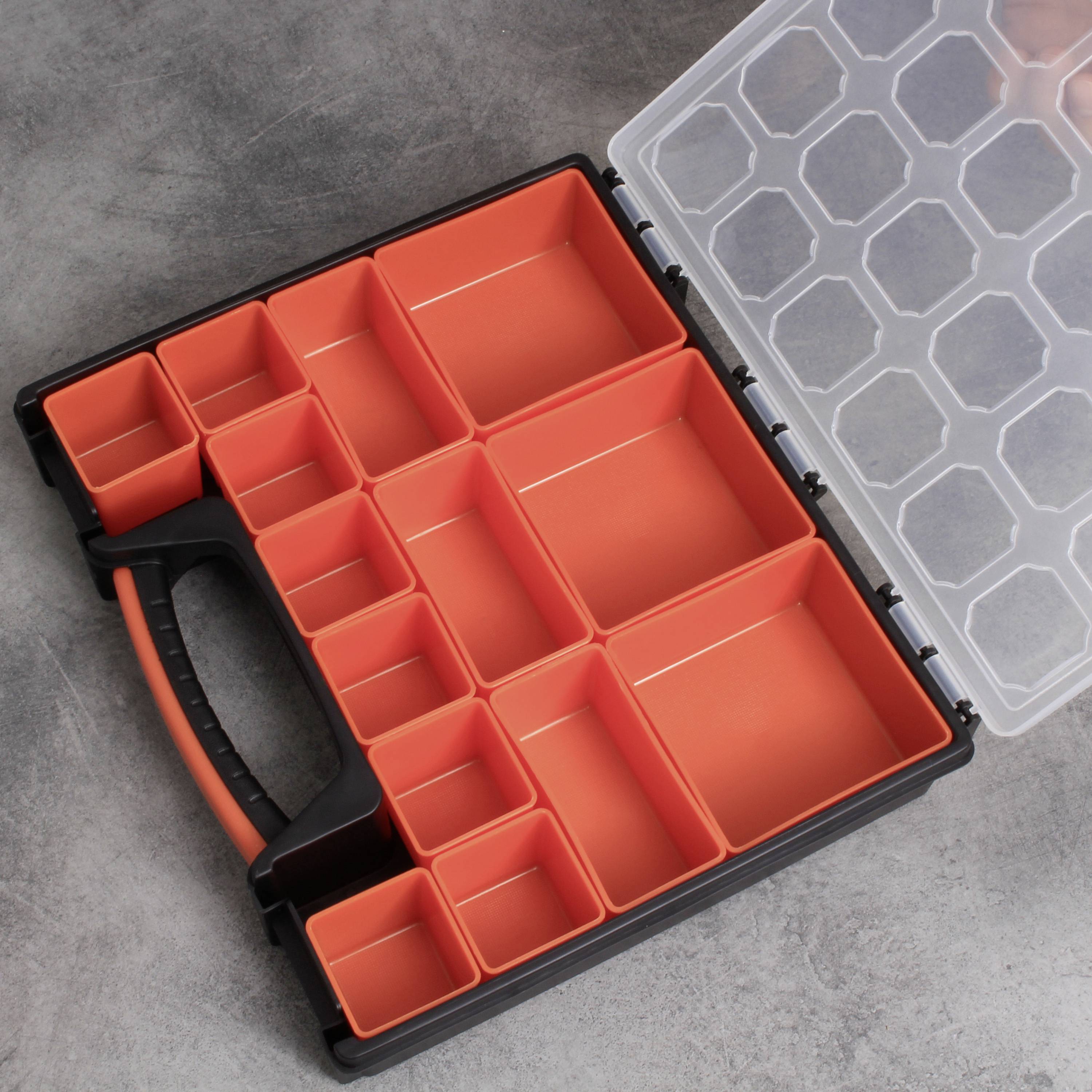 Ein geöffneter, leerer Werkzeugkasten mit mehreren kleinen, orangefarbenen Fächern, auf einem grauen Hintergrund liegend.