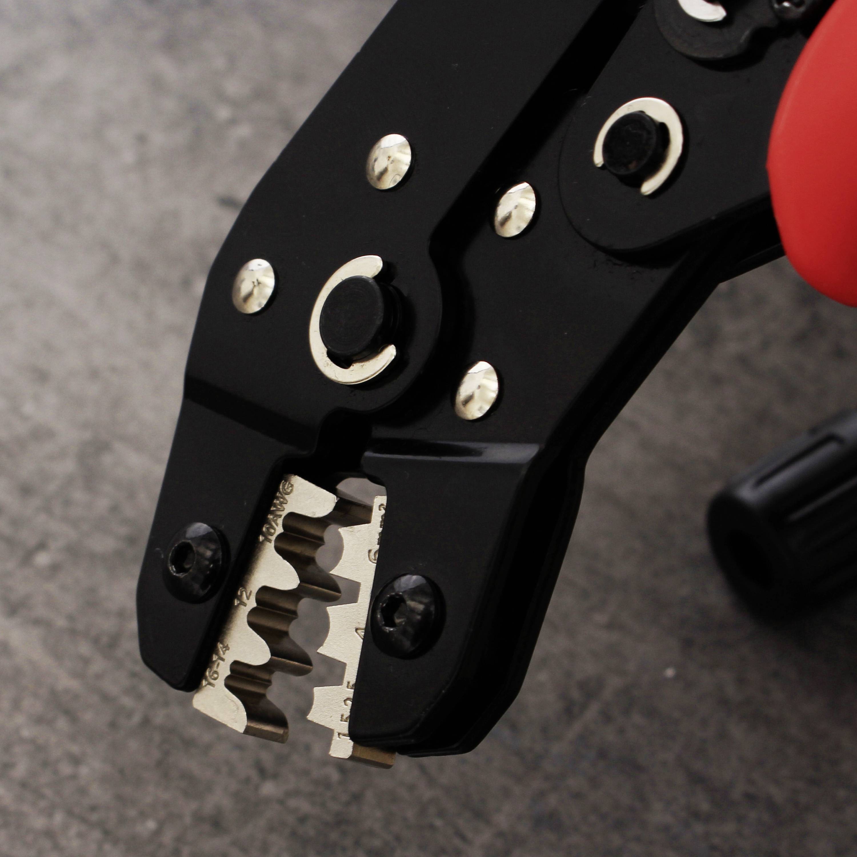 Crimpzange mit rotem Griff, auf einem Tisch liegend. Die Zange hat Metallzähne zum Pressen von Drähten.