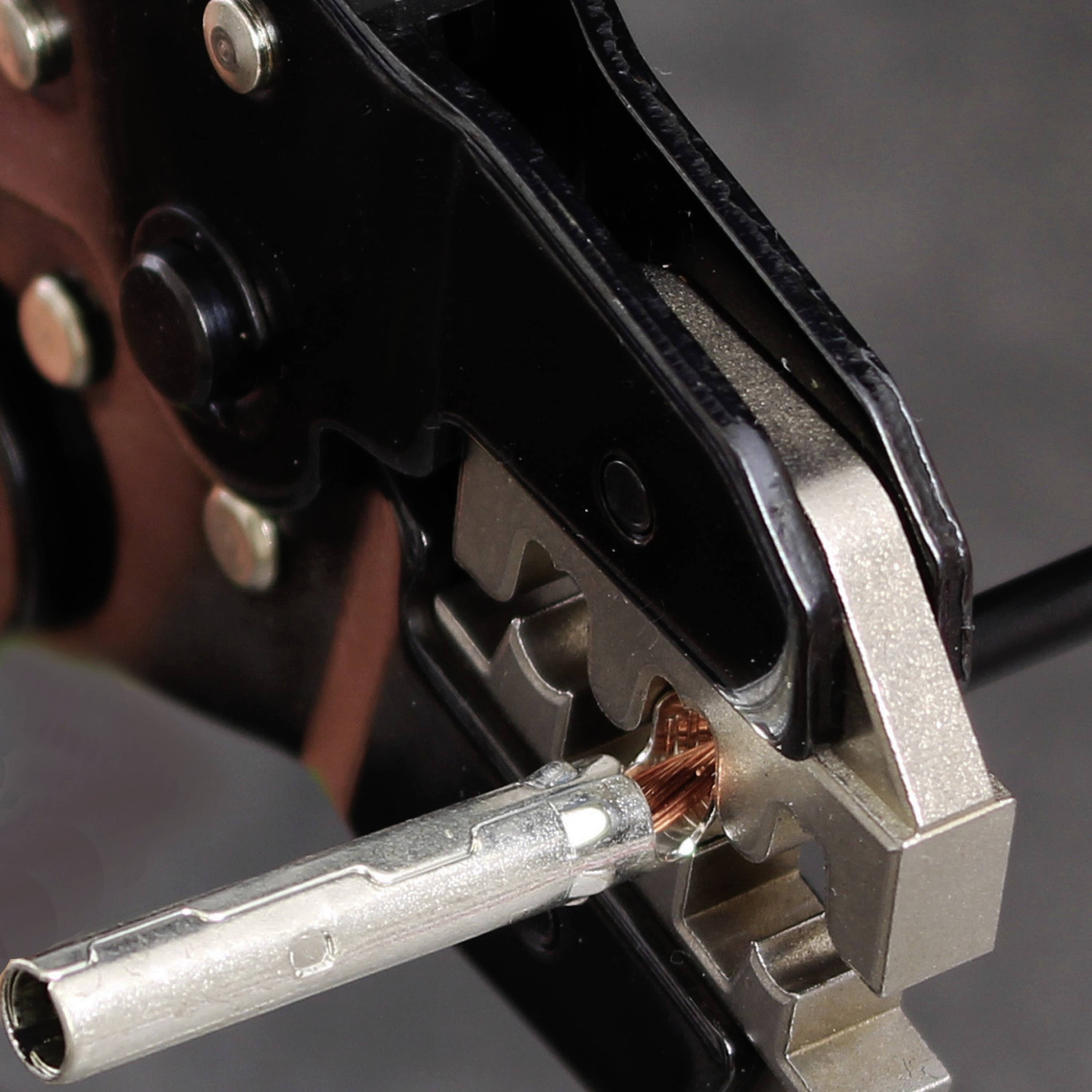 Nahaufnahme eines Crimpwerkzeugs, das ein Kabelende mit einem Metallanschluss verbindet.