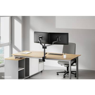 Zwei Monitore an einem Doppelschwenkarmhalter befestigt auf einem modernen Schreibtisch in einem hellen Büro mit Stuhl.
