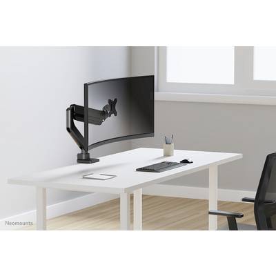 Ein leerer Schreibtisch mit gebogenem Monitorhalterungsarm, Tastatur und Maus; Fenster im Hintergrund.