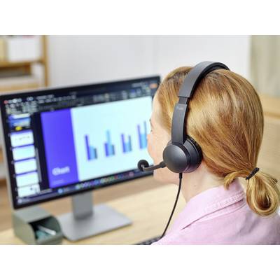 Eine Person mit Headset betrachtet ein Balkendiagramm auf einem Computermonitor, das vermutlich eine Präsentation oder Statistik zeigt.