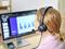Eine Person mit Headset betrachtet ein Balkendiagramm auf einem Computermonitor, das vermutlich eine Präsentation oder Statistik zeigt.