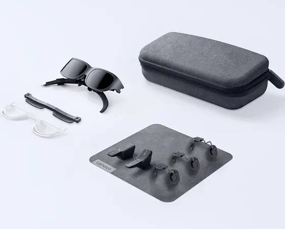 'Lenovo AR-Brillen-Set mit schwarzem Etui, zwei Brillen und mehreren zusätzlichen Komponenten auf grauer Unterlage präsentiert.'