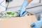 Person mit blauen Handschuhen öffnet eine Pappschachtel mit Tiefkühl-Erbsen.