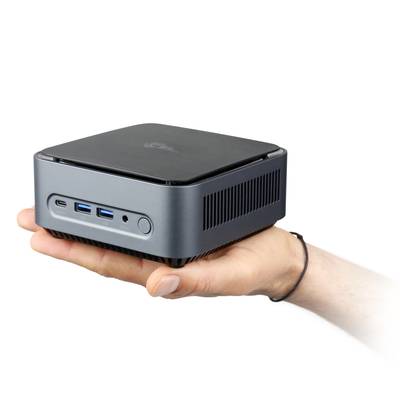 Eine Hand hält einen kompakten, quadratischen Mini-PC mit mehreren USB-Anschlüssen an der Vorderseite.