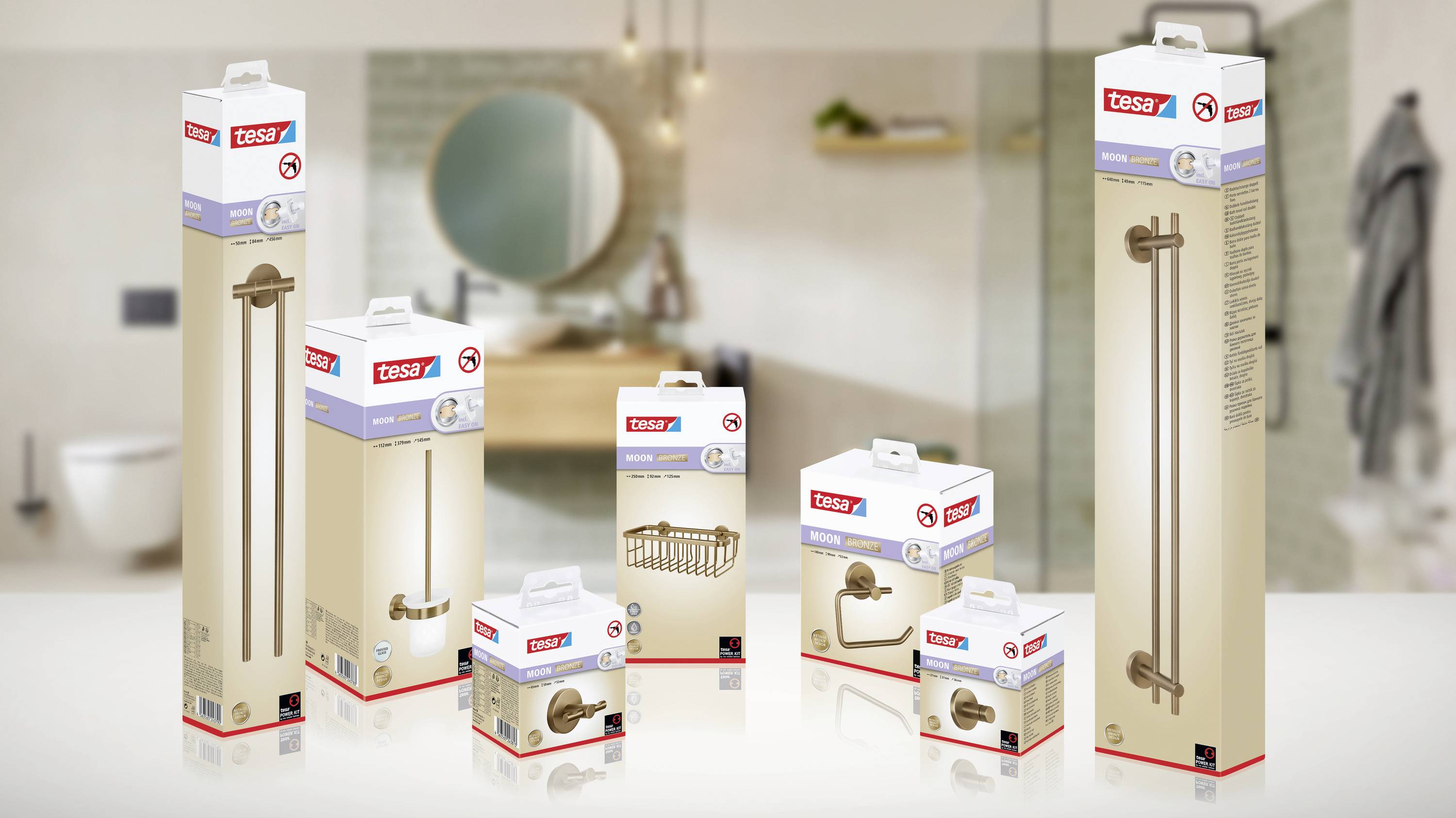 Verpackungen von Tesa-Produkten, darunter Haltegriffe und Handtuchhalter, vor einem Badezimmerhintergrund.