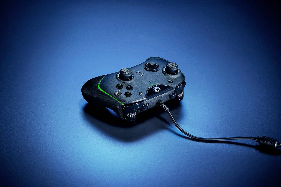 Ein schwarzer Spielcontroller mit Kabel liegt auf einer Oberfläche mit blauem Lichteffekt. Der Controller hat zwei Joysticks und mehrere Tasten.