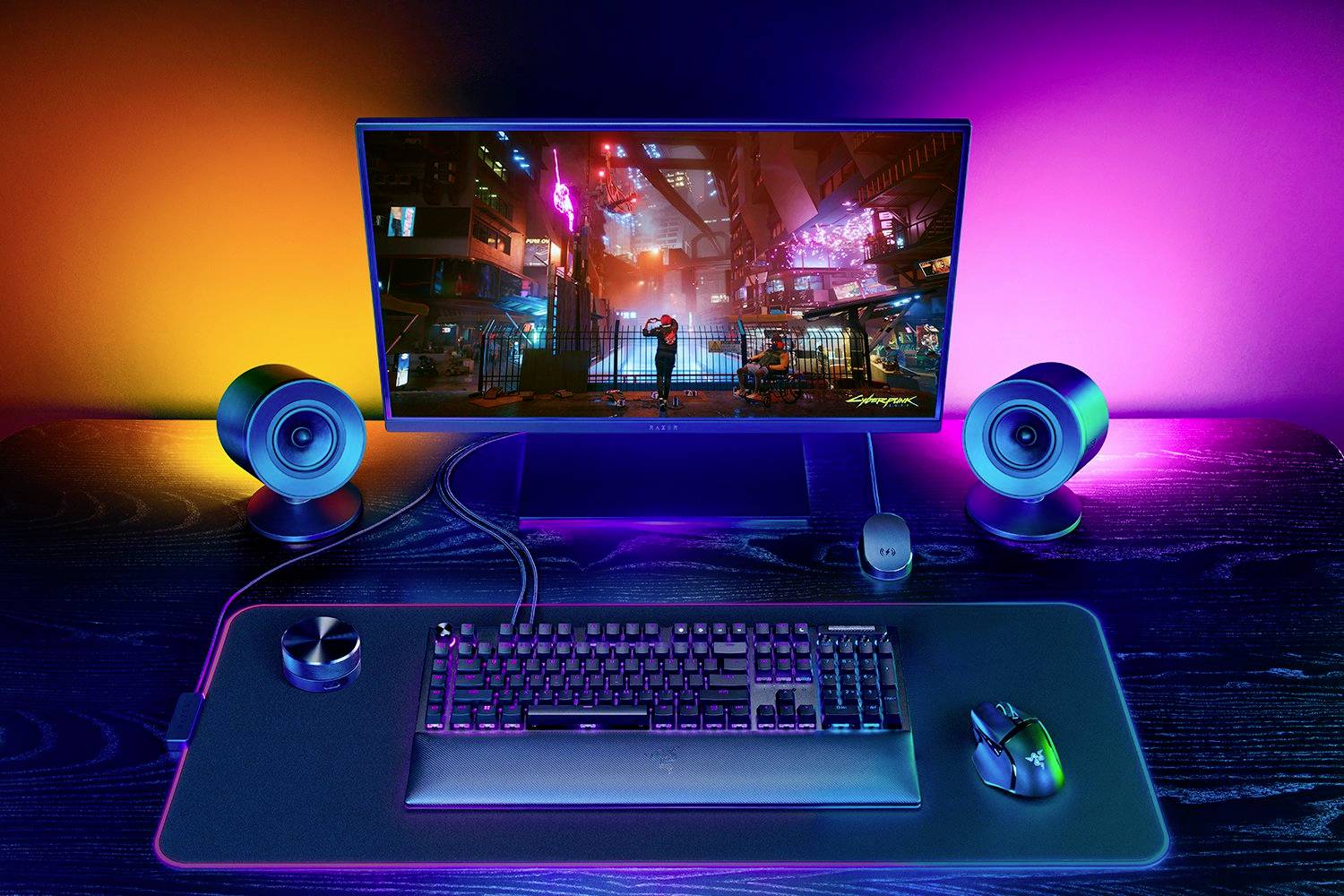 Computer-Setup auf einem Schreibtisch mit farbenfroher Hintergrundbeleuchtung; ein Bildschirm zeigt ein futuristisches Stadtbild.