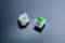 Zwei mechanische Tastaturschalter, einer liegend und einer stehend, auf einer glatten, dunklen Oberfläche.