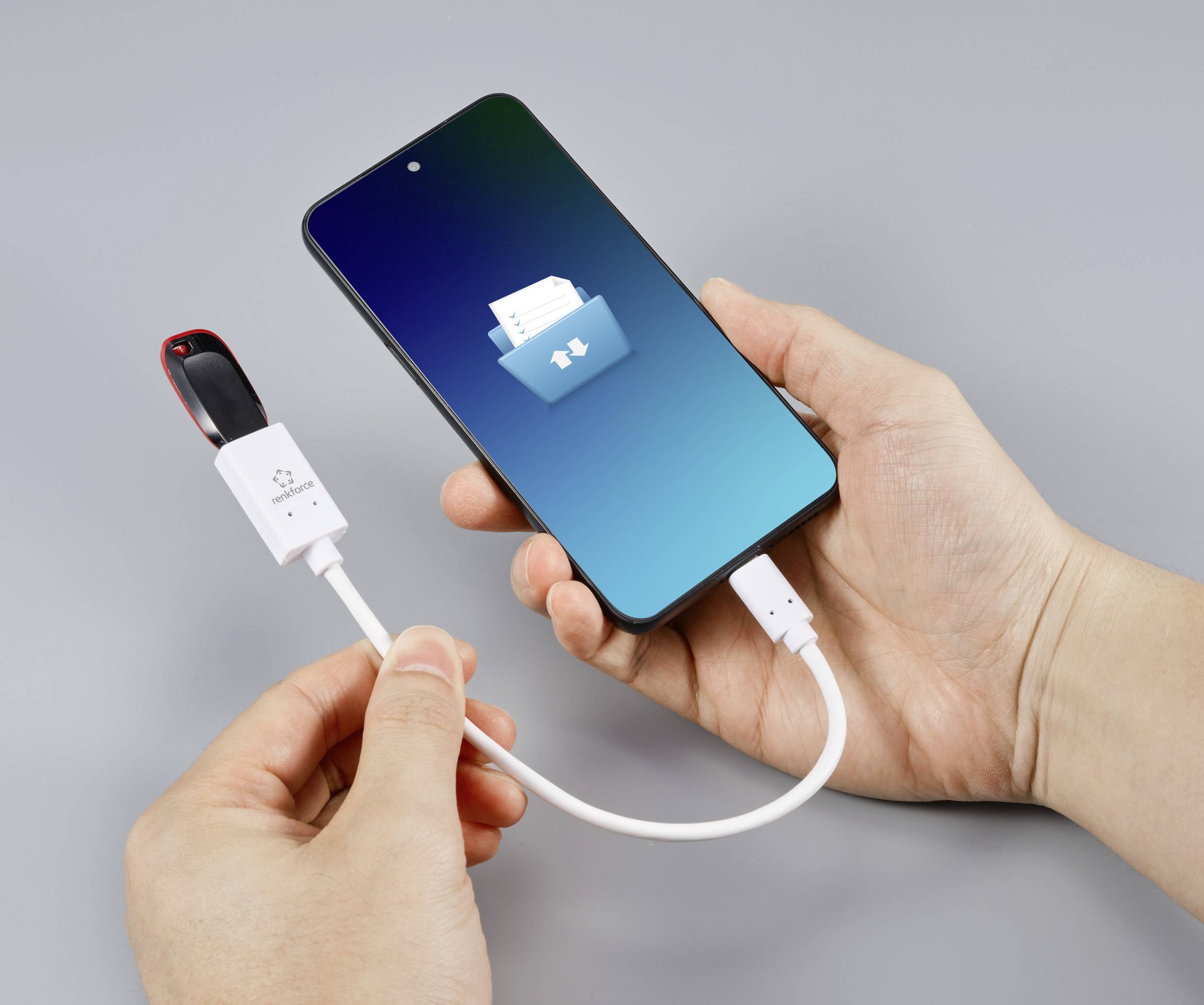 Person verbindet USB-Laufwerk mit einem Smartphone über ein Kabel. Auf dem Bildschirm des Smartphones ist ein Ordnersymbol zu sehen.