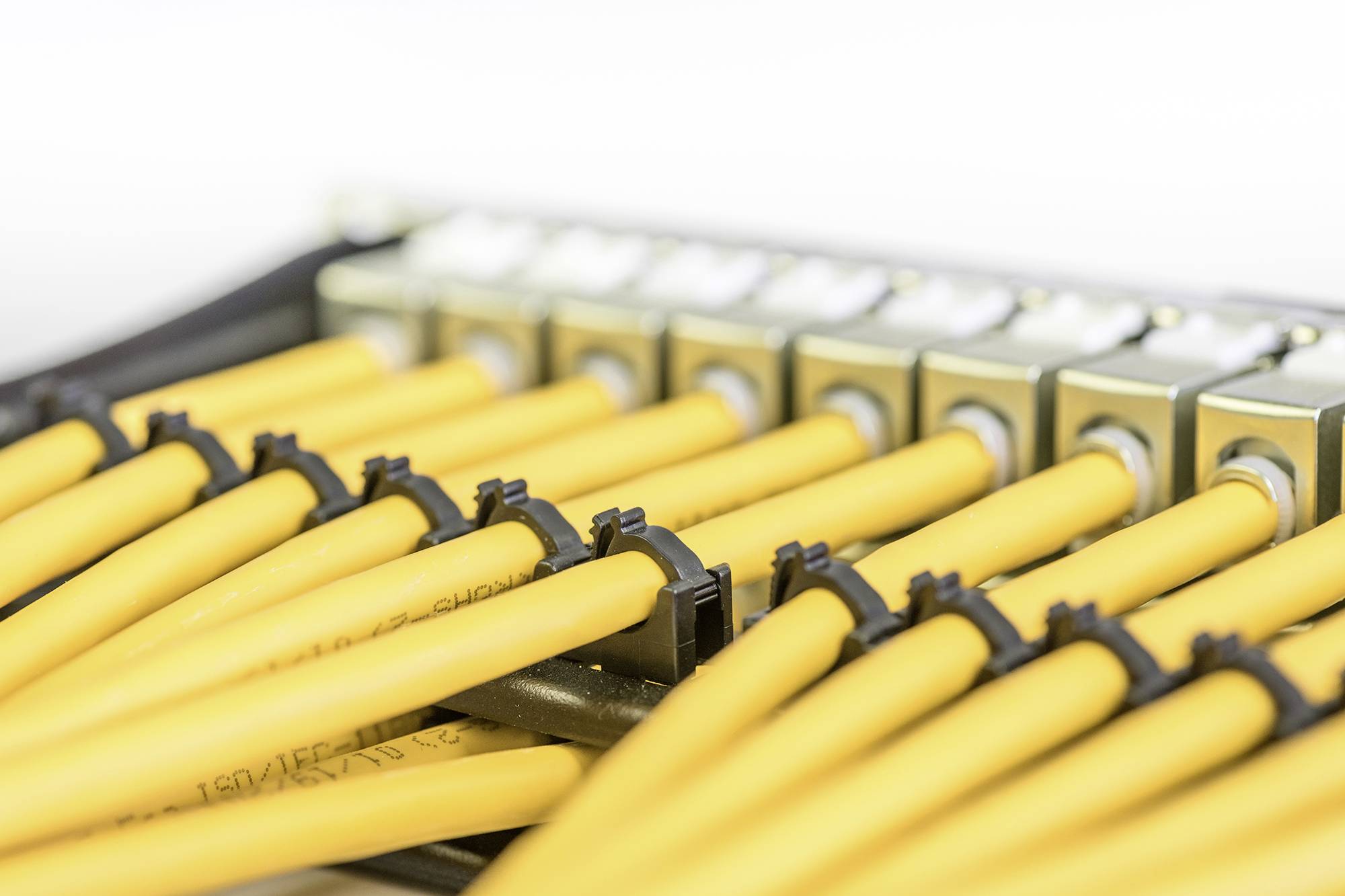 Gelbe Kabel sind in eine Reihe von Anschlüssen eingesteckt. Sie sind sauber geordnet und bilden einen strukturierten Kabelbaum.