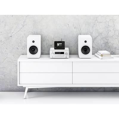 Weiße Kommode mit zwei Lautsprechern, einem Stereo-Verstärker und kleinen gestapelten Büchern in einem modernen Wohnraum.