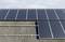 Solarmodule auf einem Wellblechdach unter blauem Himmel. Panels sind in zwei Reihen angeordnet und profitieren von direktem Sonnenlicht.