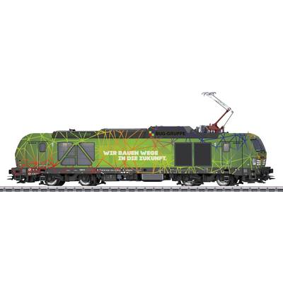 Grüner Zug mit buntem Linienmuster, Slogan 'Wir bauen Wege in die Zukunft' auf der Seite, steht ruhig auf Gleisen.
