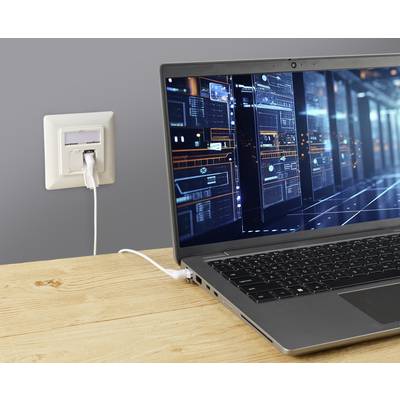 Ein geöffneter Laptop auf einem Holztisch ist mit einem Netzwerkanschluss verbunden. Auf dem Bildschirm sind technische Diagramme zu sehen.